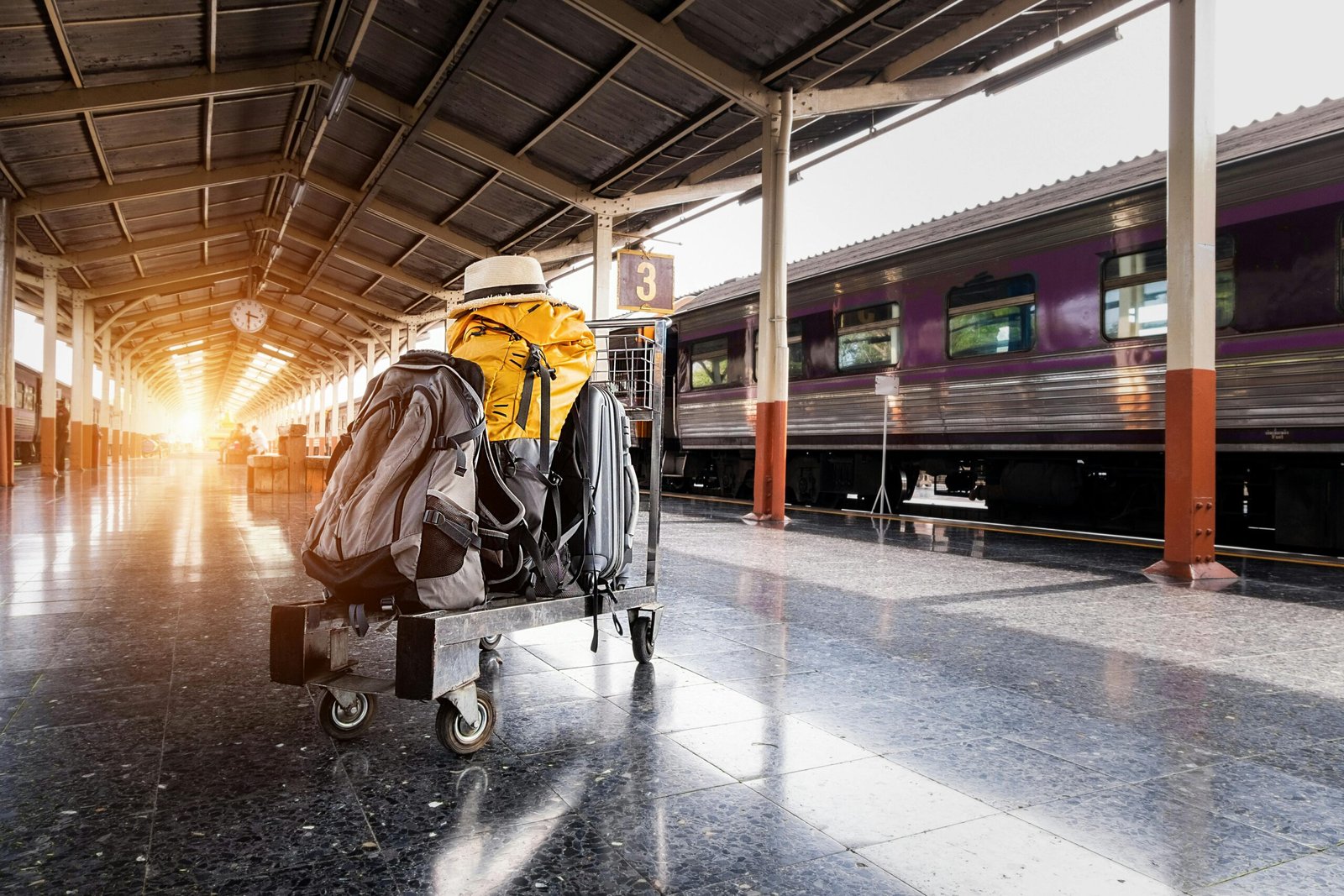 A traveler's baggage cart on an urban railway station platform at sunrise.