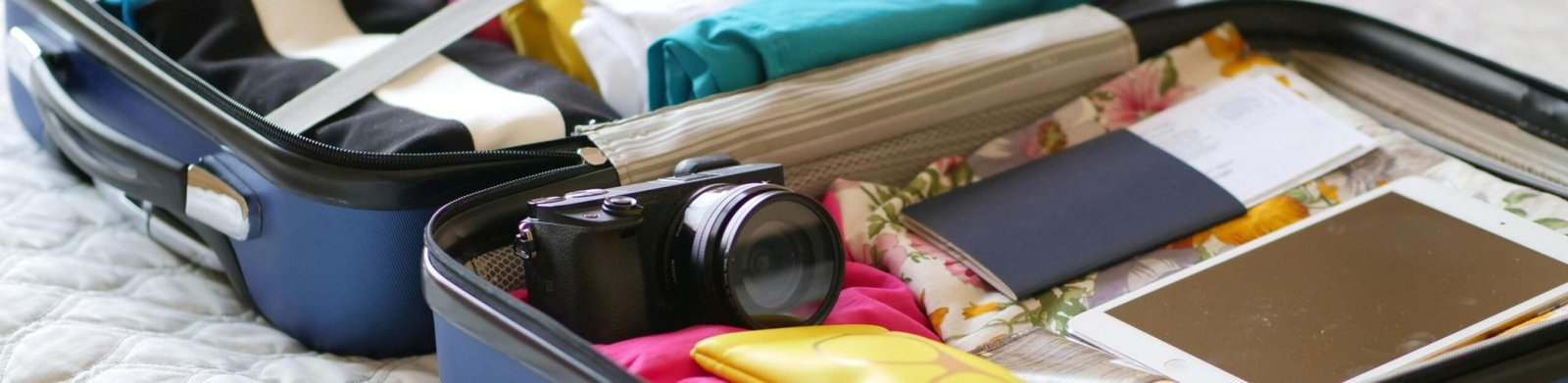 pexels-photo-8212224-8212224-1 Open suitcase with camera, clothes, and passport, ready for a summer vacation.